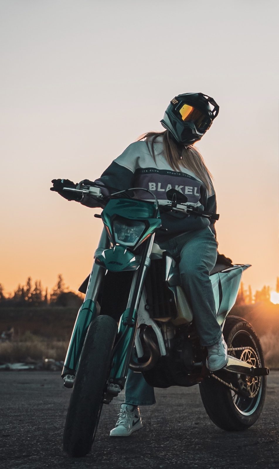 Alaïa sur sa supermotard en sweat streetwear au coucher du soleil